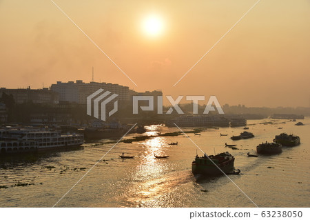 Dhaka in Bangladesh Beautiful sunrise and old cityscape Passenger ship that stops along the Brigonga River Large and small boats crossing the river 63238050