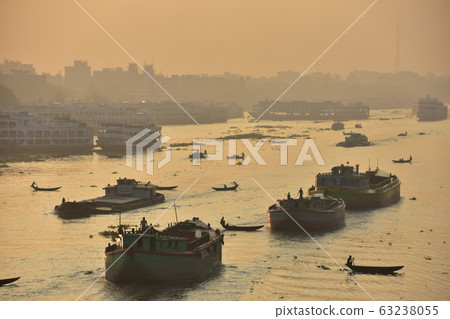 Dhaka in Bangladesh Beautiful sunrise and old cityscape Passenger ship that stops along the Brigonga River Large and small boats crossing the river 63238055
