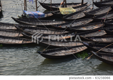Dhaka, Bangladesh Many small boats parked along the Brigonga River Man working with a man sleeping on a mosquito net on board 63238066