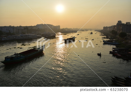 Dhaka in Bangladesh Beautiful sunrise and old cityscape Passenger ship that stops along the Brigonga River Large and small boats crossing the river 63238070