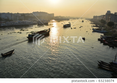 Dhaka in Bangladesh Beautiful sunrise and old cityscape Passenger ship that stops along the Brigonga River Large and small boats crossing the river 63238074