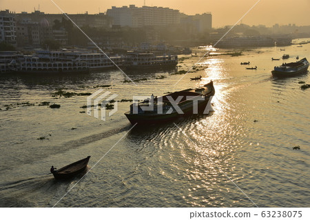 Dhaka in Bangladesh Beautiful sunrise and old cityscape Passenger ship that stops along the Brigonga River Large and small boats crossing the river 63238075