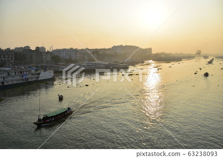 Dhaka in Bangladesh Beautiful sunrise and old cityscape Passenger ship that stops along the Brigonga River Large and small boats crossing the river 63238093