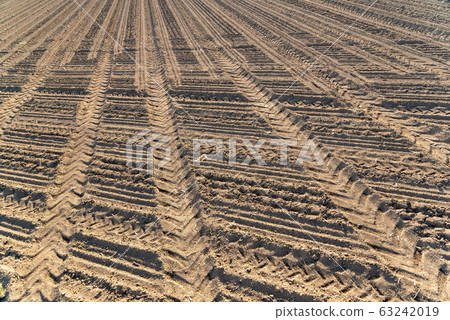 Plowed field brown soil tractor tracks 63242019