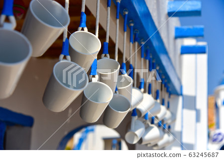 White mugs hang in a greek street cafe White mugs hang in a greek street cafe 63245687