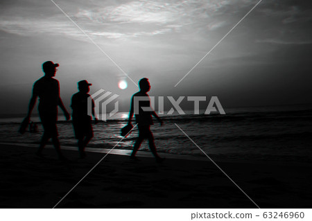 silhouettes of men on the beach by the sea on the background of sunrise 63246960
