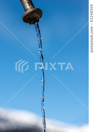 Fresh water flowing from a faucet on a clear blue sky Fresh water flowing from a faucet on a clear blue sky 63248504