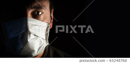 portrait of a man in a medical mask in a low key. a worldwide tragedy. COVID-19 virus pandemic warning portrait of a man in a medical mask in a low key. a worldwide tragedy. COVID-19 virus pandemic warning 63248768