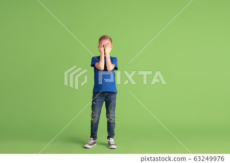 Happy boy playing and having fun on green studio background, emotions 63249976