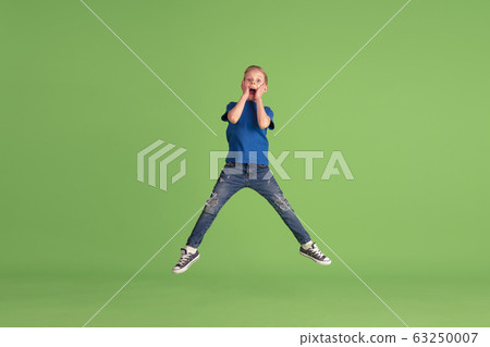Happy boy playing and having fun on green studio background, emotions 63250007