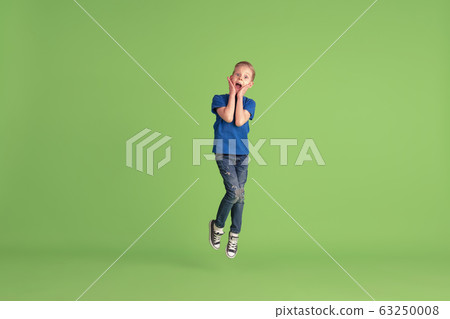 Happy boy playing and having fun on green studio background, emotions Happy boy playing and having fun on green studio background, emotions 63250008