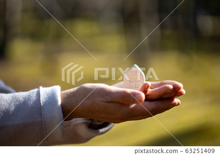 Small house on the palm of a woman 63251409