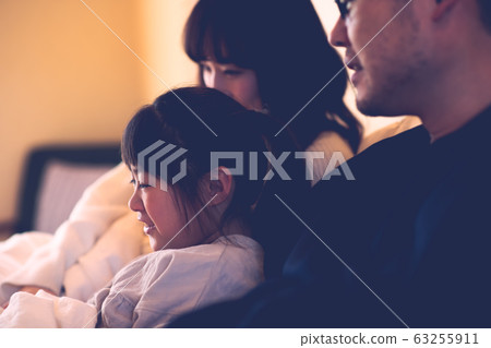 在床上躺在床上看電影的三個父母和孩子(父親,母親,女兒)的圖像(電影風格) 在床上躺在床上看電影的三個父母和孩子(父親,母親,女兒)的圖像(電影風格) 63255911