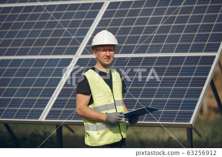 Man in a white helmet near a solar panel 63256912
