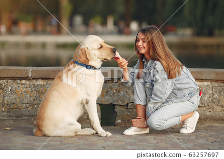Girl walking in a spring sity with cute dog Girl walking in a spring sity with cute dog 63257697