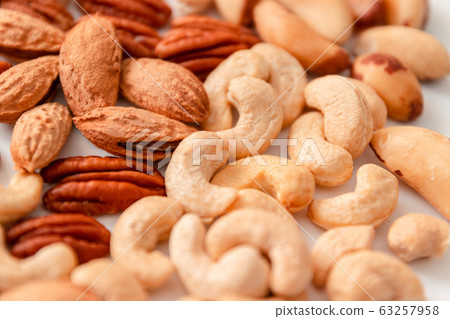 Assorted brown nuts on a gray background. Macadamia, cashews, minced almonds, pecans, wholesome food 63257958