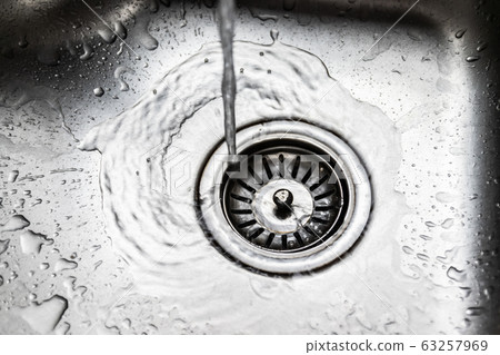 Water flowing down the hole into the stainless steel sink Water flowing down the hole into the stainless steel sink 63257969