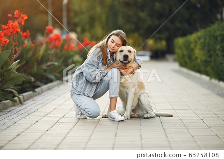 Girl walking in a spring sity with cute dog 63258108