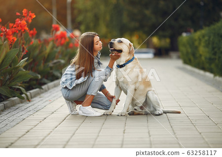 Girl walking in a spring sity with cute dog 63258117