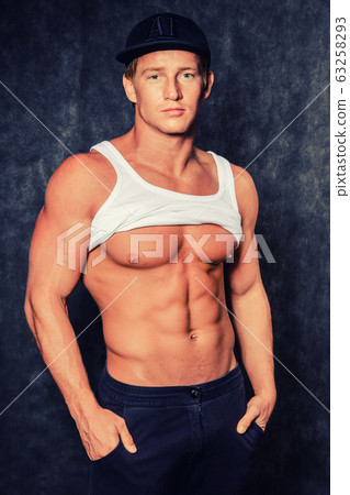 Muscular man  in  vest and  cap with a naked torso 63258293