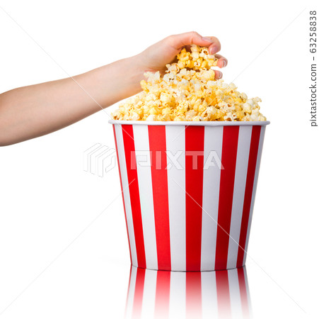 Woman hand picking popcorn from striped bucket isolated on white background Woman hand picking popcorn from striped bucket isolated on white background 63258838