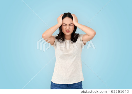 Coronavirus Concept. Chinese woman standing isolated on grey holdinghead having headache wincing from pain 63261643