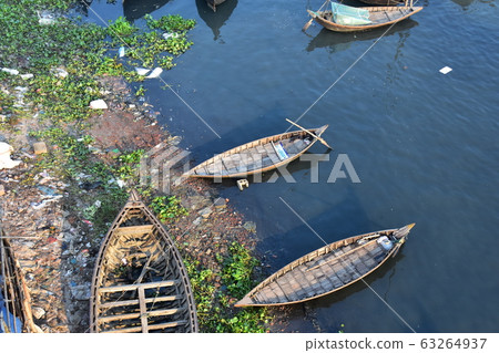 Dhaka, Bangladesh Many small boats parked on the Brigonga River and a Bangladeshi man sleeping on a mosquito net on board Dhaka, Bangladesh Many small boats parked on the Brigonga River and a Bangladeshi man sleeping on a mosquito net on board 63264937