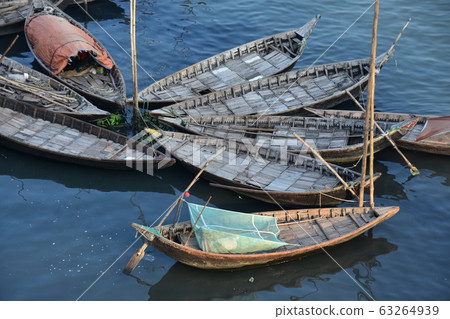 Dhaka, Bangladesh Many small boats parked on the Brigonga River and a Bangladeshi man sleeping on a mosquito net on board 63264939