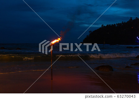 Burning torch on the sandy beach of the ocean 63270043