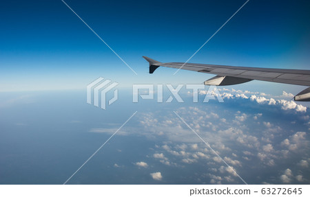 Wing of airplane over white clouds 63272645