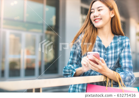Smiling young Asian woman with shopping colour Smiling young Asian woman with shopping colour 63275416