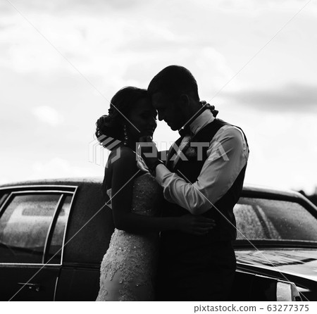Silhouette of bride and groom near car Silhouette of bride and groom near car 63277375
