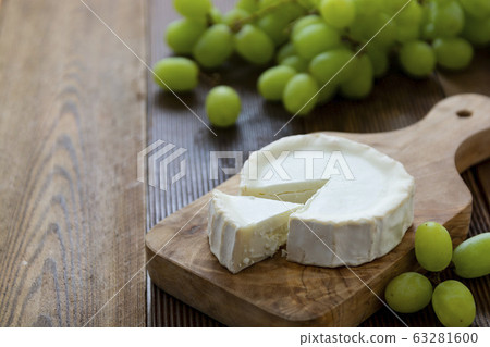 Goat cheeses with grapes, on wooden background isolated. Dark food photo. 63281600