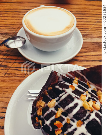 Cup of coffee and chocolate muffin on wooden table in cafe Cup of coffee and chocolate muffin on wooden table in cafe 63281684