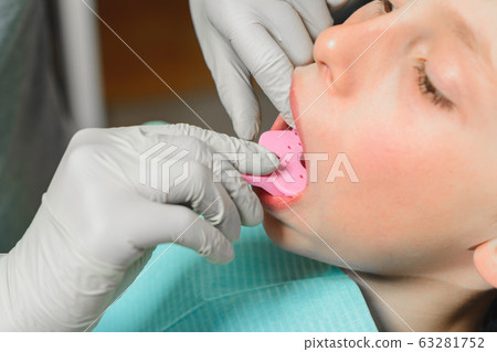 The boy orthodontist makes a fitting for the The boy orthodontist makes a fitting for the 63281752
