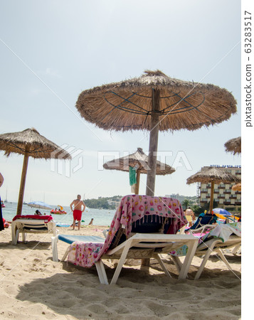 The beaches of Mallorca lined with beach umbrellas and beach beds made of straw under the clear and shining sun 63283517