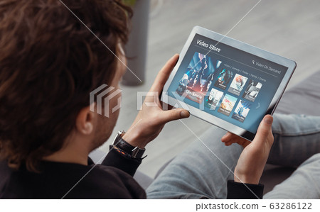 Man using tablet for watching VOD service Man using tablet for watching VOD service 63286122