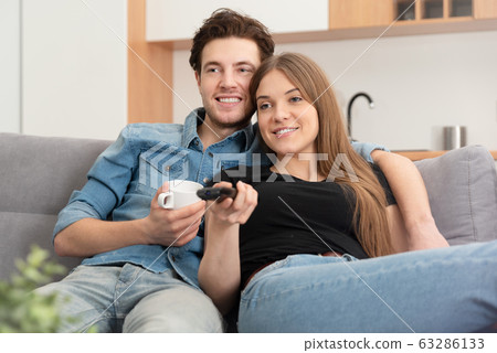 Young couple watching TV on sofa Young couple watching TV on sofa 63286133