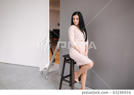 Elegant brunette woman in stylish dress posing in studio on gray background 63286916