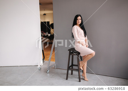 Elegant brunette woman in stylish dress posing in studio on gray background 63286918