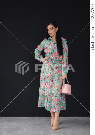 Young woman model demonstrating cloths on black background. Beautiful spring dress 63287200