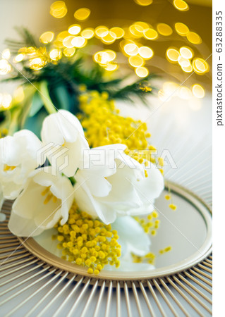 Bouquet of white tulips and mimosa flowers on mirror tray 63288335