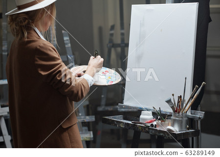 Young contemporary woman with color palette mixing colors before painting Young contemporary woman with color palette mixing colors before painting 63289149