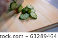 Cut the cucumber. Cypress cutting board. 63289464