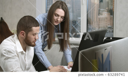 Young woman giving explanations to her coworker 63289741