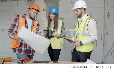 Young architects check new blueprints for a building Young architects check new blueprints for a building 63289745