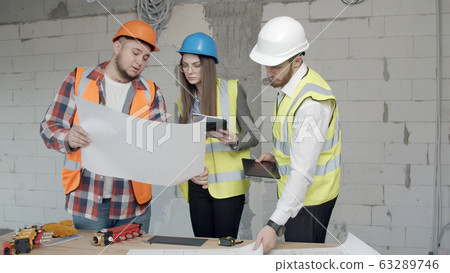 Young architects check new blueprints for a building Young architects check new blueprints for a building 63289746