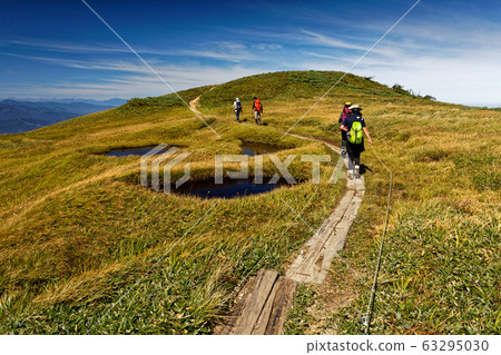 Mountain climber going down the mountain ridge line Mountain climber going down the mountain ridge line 63295030