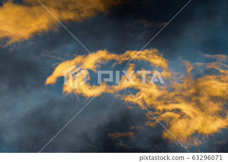 Fluffy thunderstorm clouds illuminated by disappearing rays at sunset and dark thunderclouds floating across blue sky to change season weather 63296071