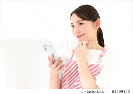 在圍裙中操作智能手機的女人的形象 63299530